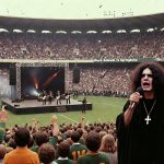 Black Sabbath performs a legendary live show on a makeshift stage in the middle of Durban’s Kings Park Rugby Stadium. Ozzy Osbourne, in full black robes and cross, belts out vocals in the foreground while Tony Iommi, Geezer Butler, and Bill Ward rock behind him. The massive crowd of South African rugby fans (many in Springboks jerseys) mixes metal horns with stadium cheers, as rugby balls fly through the air and a giant banner reads “Black Sabbath vs Springboks.” The retro cinematic style captures the chaotic, smoke-filled energy of a heavy metal invasion of a rugby field.